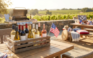 a wooden crate of assorted wine bottles on a patio table with an american flag, perfect for a memorial day wine guide.